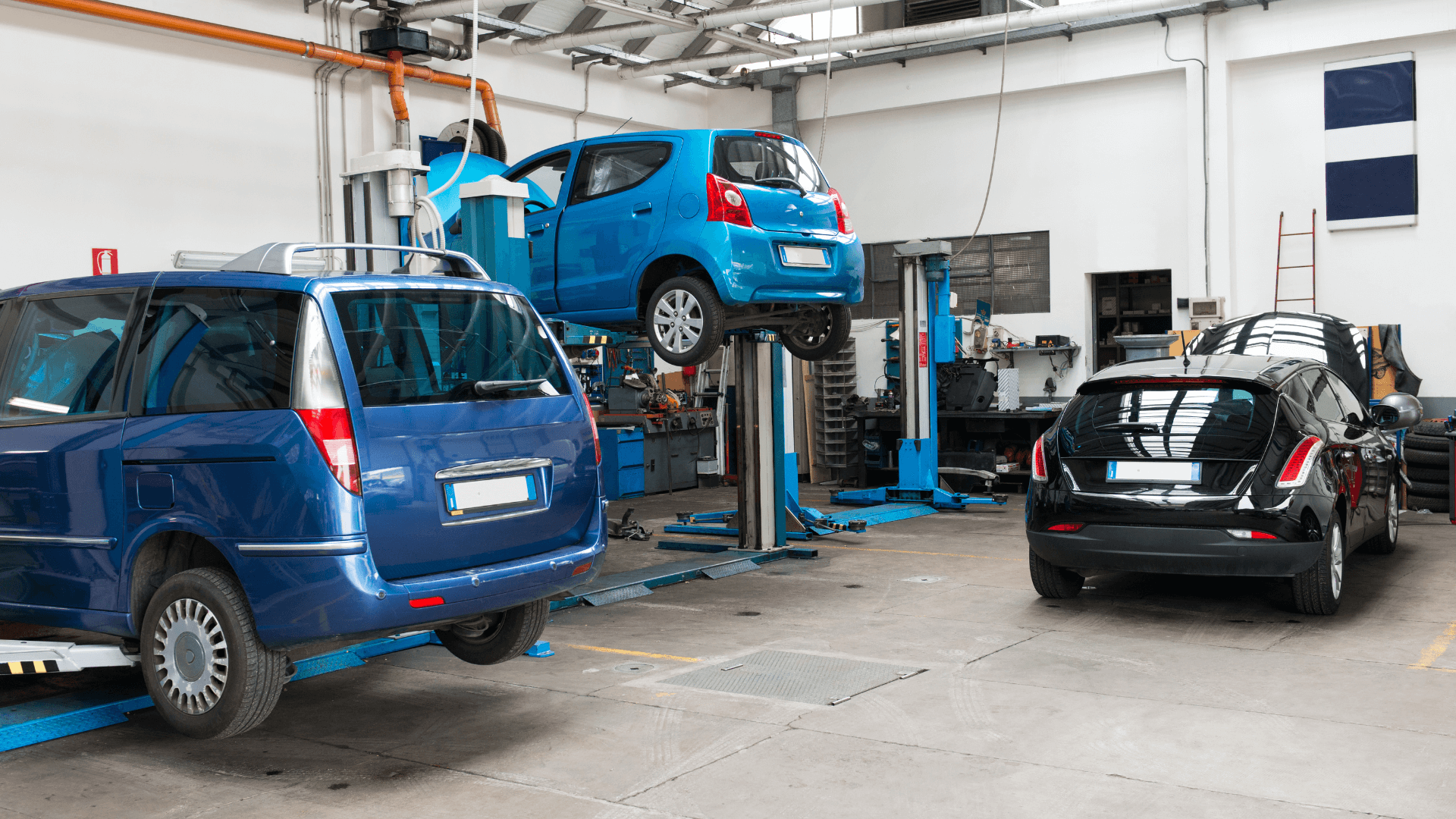 3 voitures sur un pont dans un garage auto